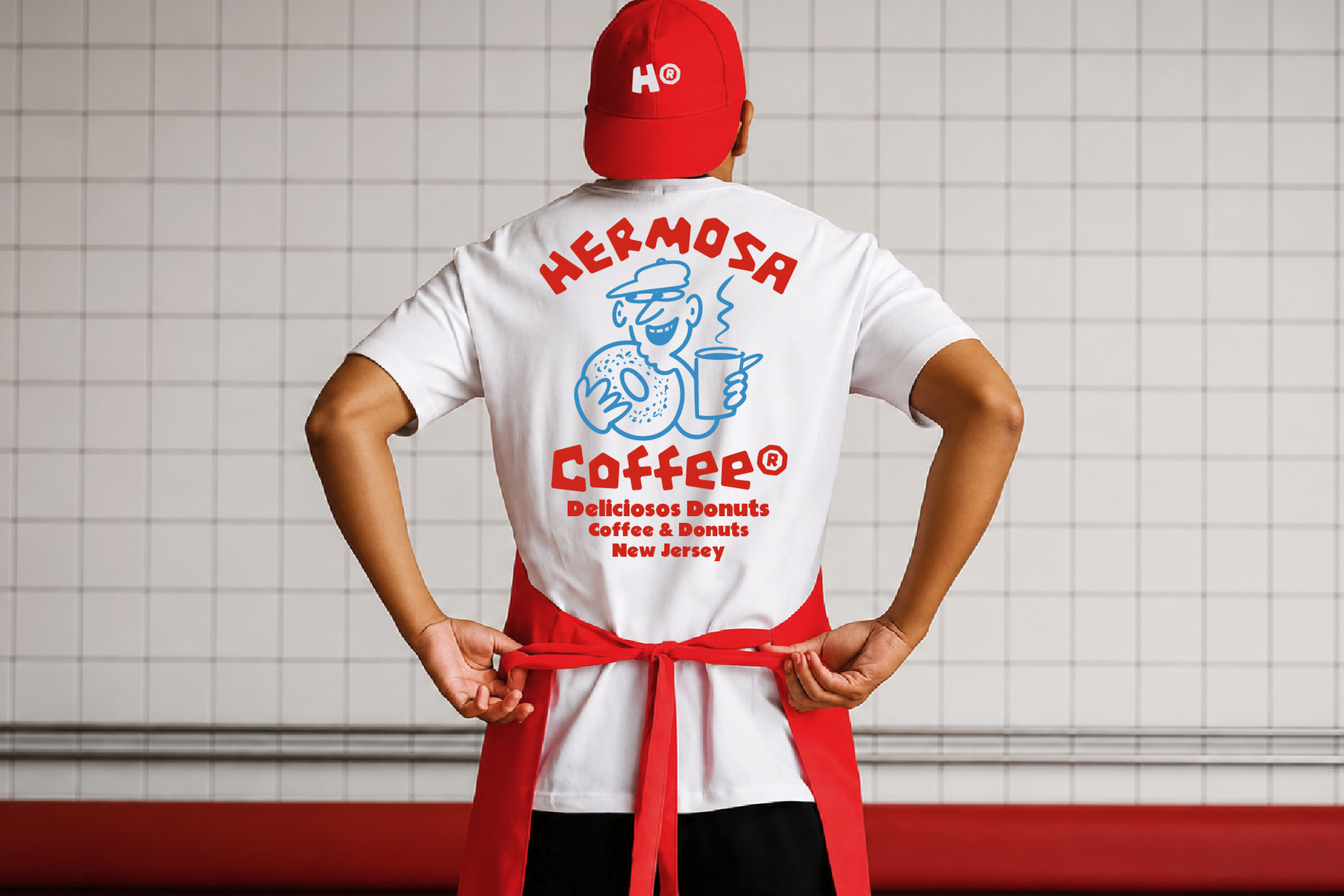 Retro coffee shop worker wearing red cap, white tee with blue cartoon chef graphic, red apron