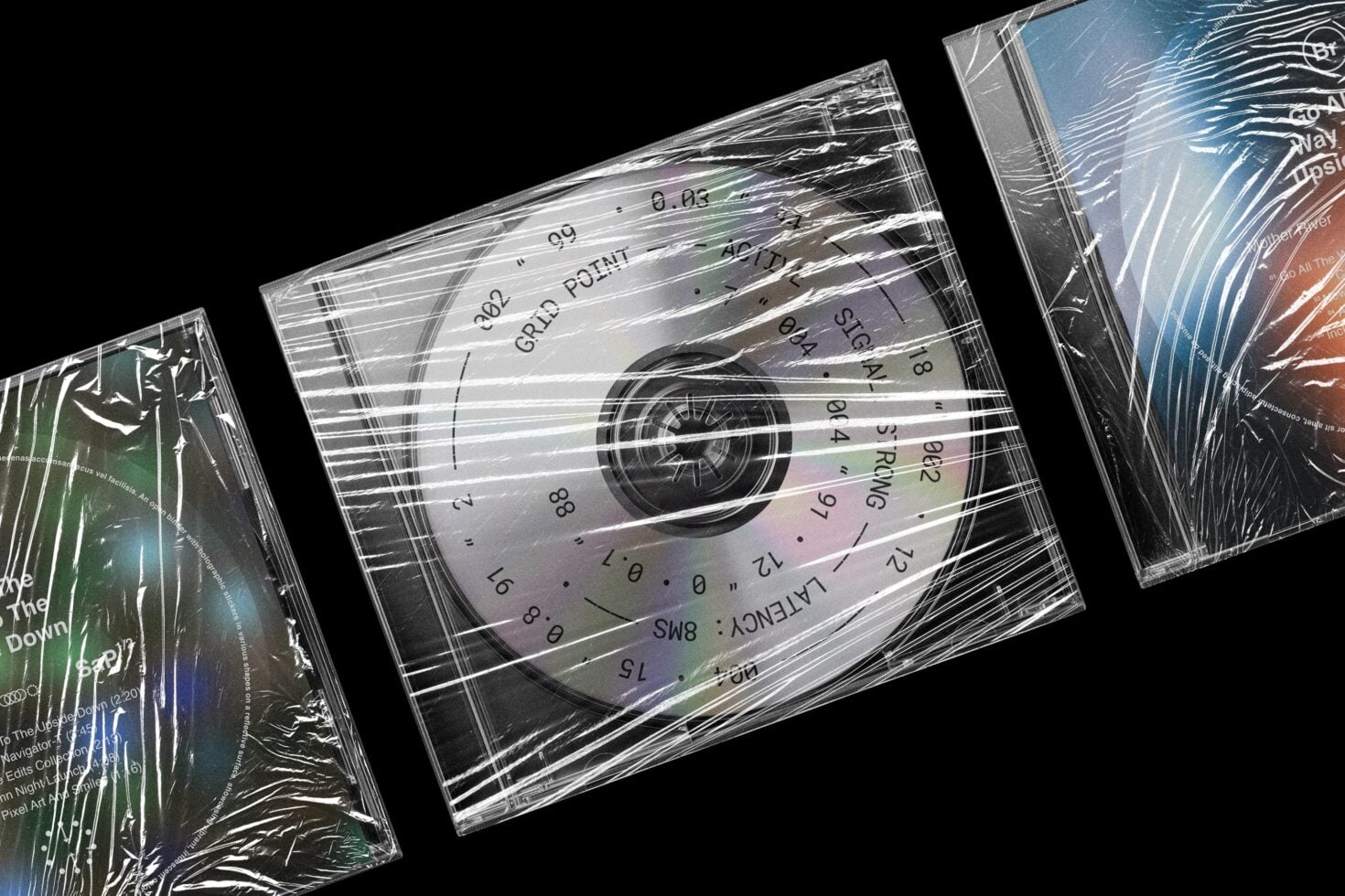CD cases in plastic shrink wrap with holographic disc designs on black background