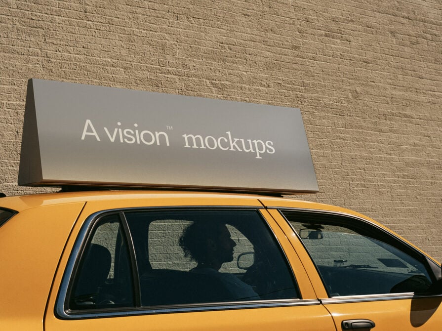 Metallic roof sign mounted on yellow taxi with brick wall backdrop