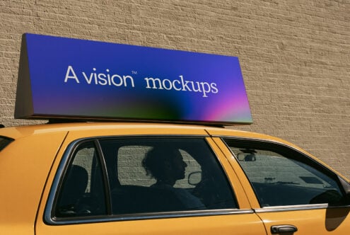 Yellow taxi with vibrant gradient rooftop ad sign against brick wall