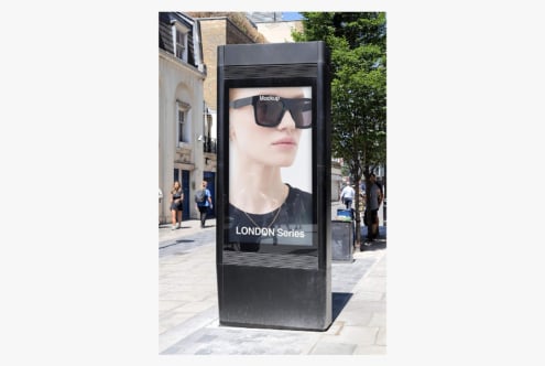 Street advertising kiosk mockup displaying sunglasses campaign on urban London sidewalk