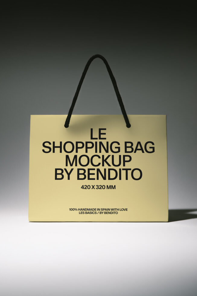 Cream paper shopping bag with black rope handles on neutral background mockup