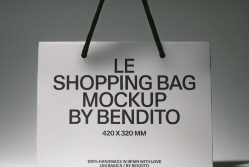 White shopping bag with black rope handles showing product text on neutral background
