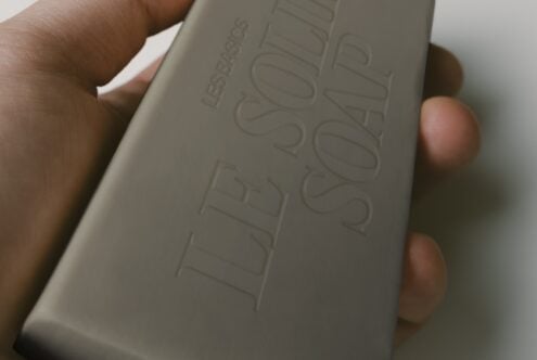 Hand holding cream colored box with embossed text, close up shot showing texture details