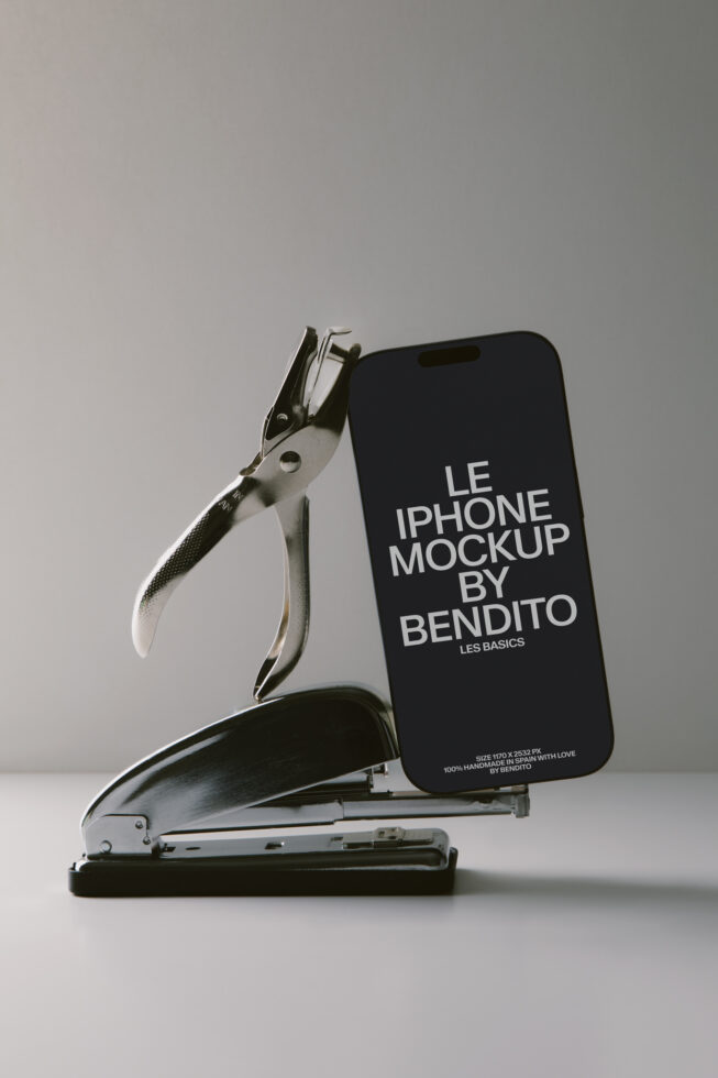 iPhone mockup leaning against vintage stapler with hole punch on neutral background
