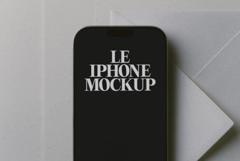 Styled iPhone mockup with serif text on black screen, shot flat lay on white paper background