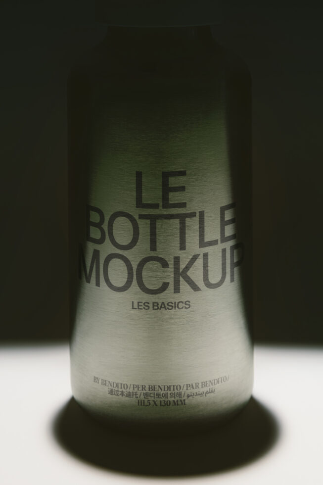 Glass bottle mockup with moody lighting showing label on frosted surface