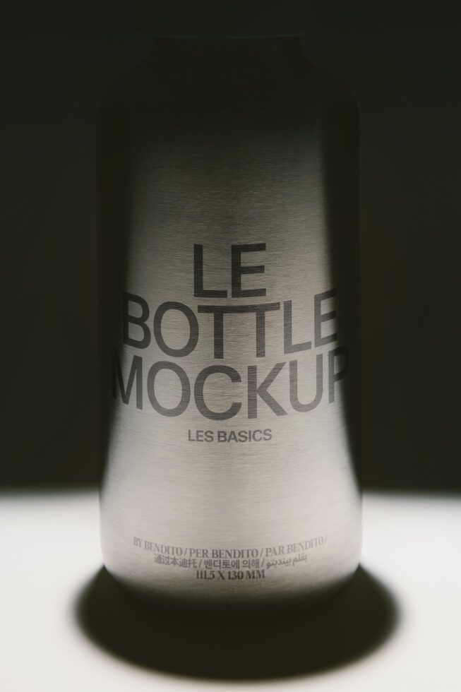 Frosted wine bottle mockup with label showing Les Basics branding on metallic surface