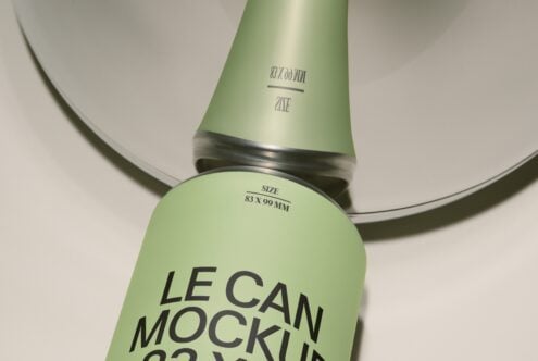 Two pale green cylindrical cans with black bands, one upright one tilted, showing label mockup space