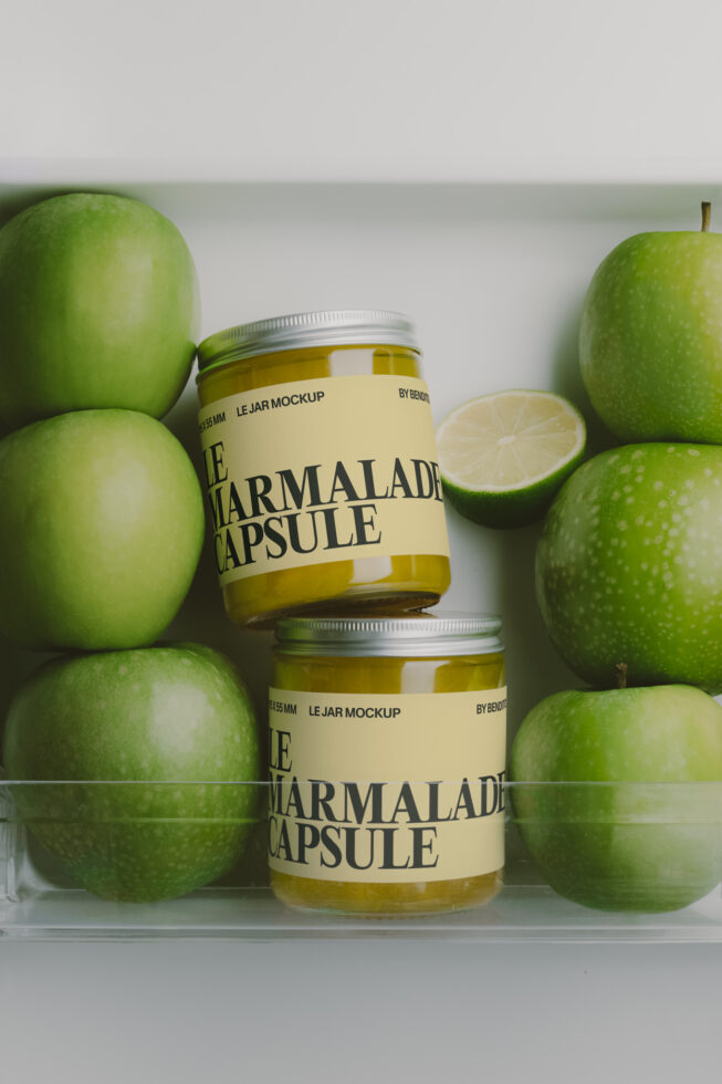 Two jam jars surrounded by fresh green apples with a sliced lime in the middle