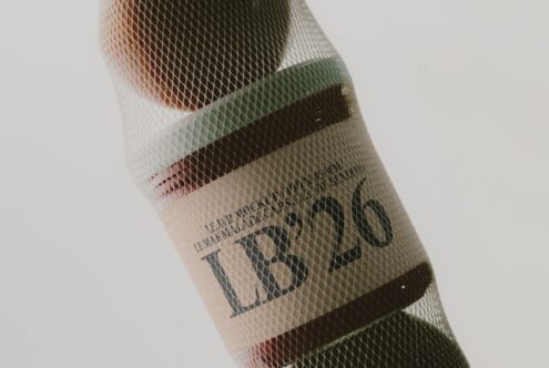 Mesh-wrapped wine bottle with layered color bands showing through textured netting material