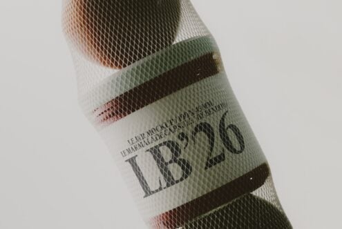 Rolled wine bottle mockup with mesh overlay showing earthy label colors, rust, sage, plus cream tones