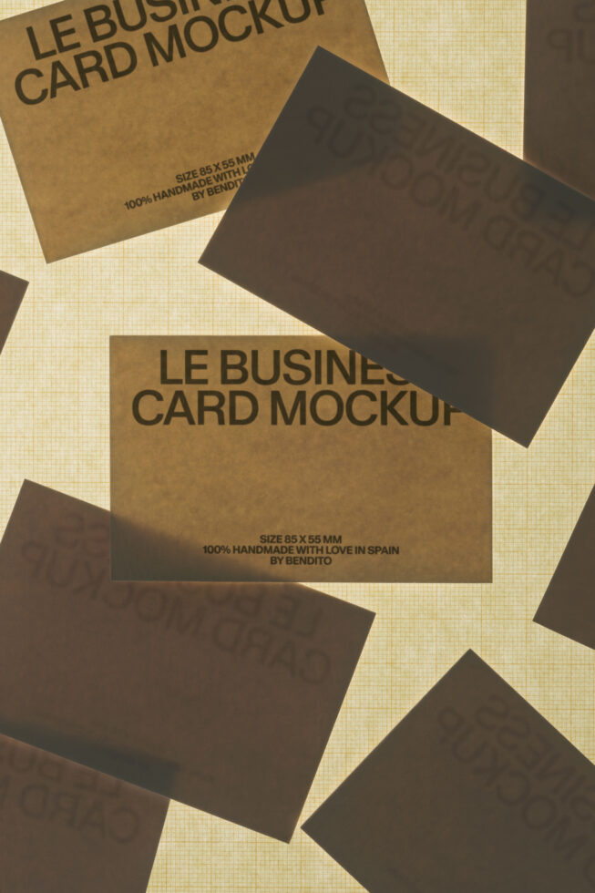 Scattered kraft paper business cards with black mockups on textured cream background