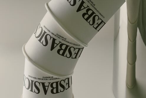 Stacked cosmetic jars with serif typography wrapping around cream-colored containers on neutral background