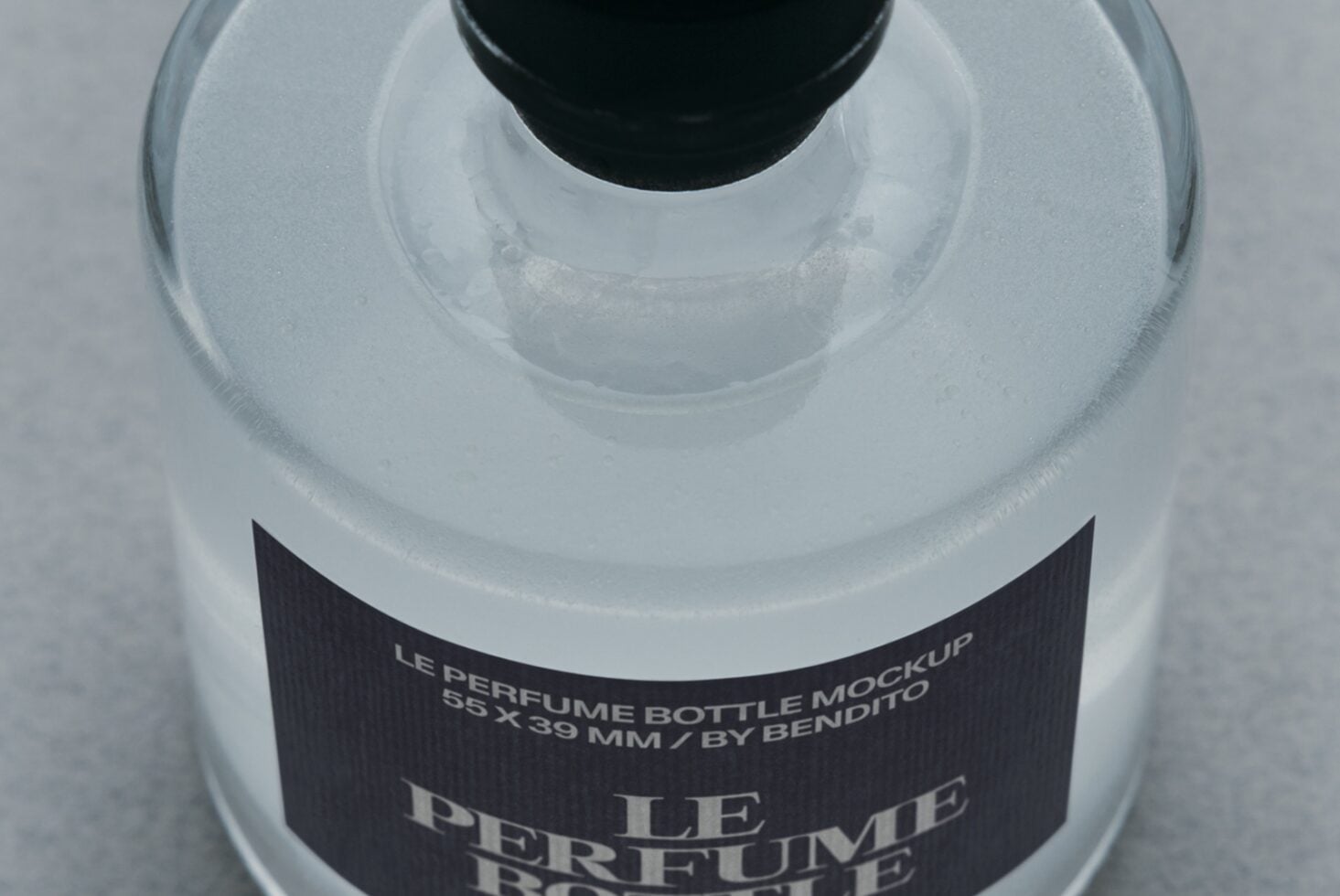 Overhead shot of frosted glass perfume bottle with black cap, dark label showing product name