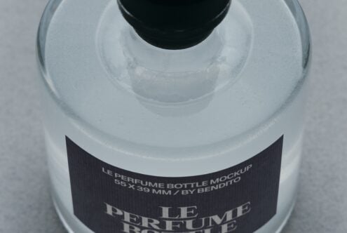 Overhead shot of frosted glass perfume bottle with black cap, dark label showing product name