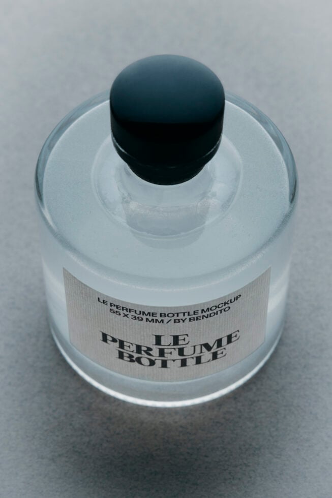 Overhead shot of frosted glass perfume bottle with black dome cap, label reads Le Perfume Bottle