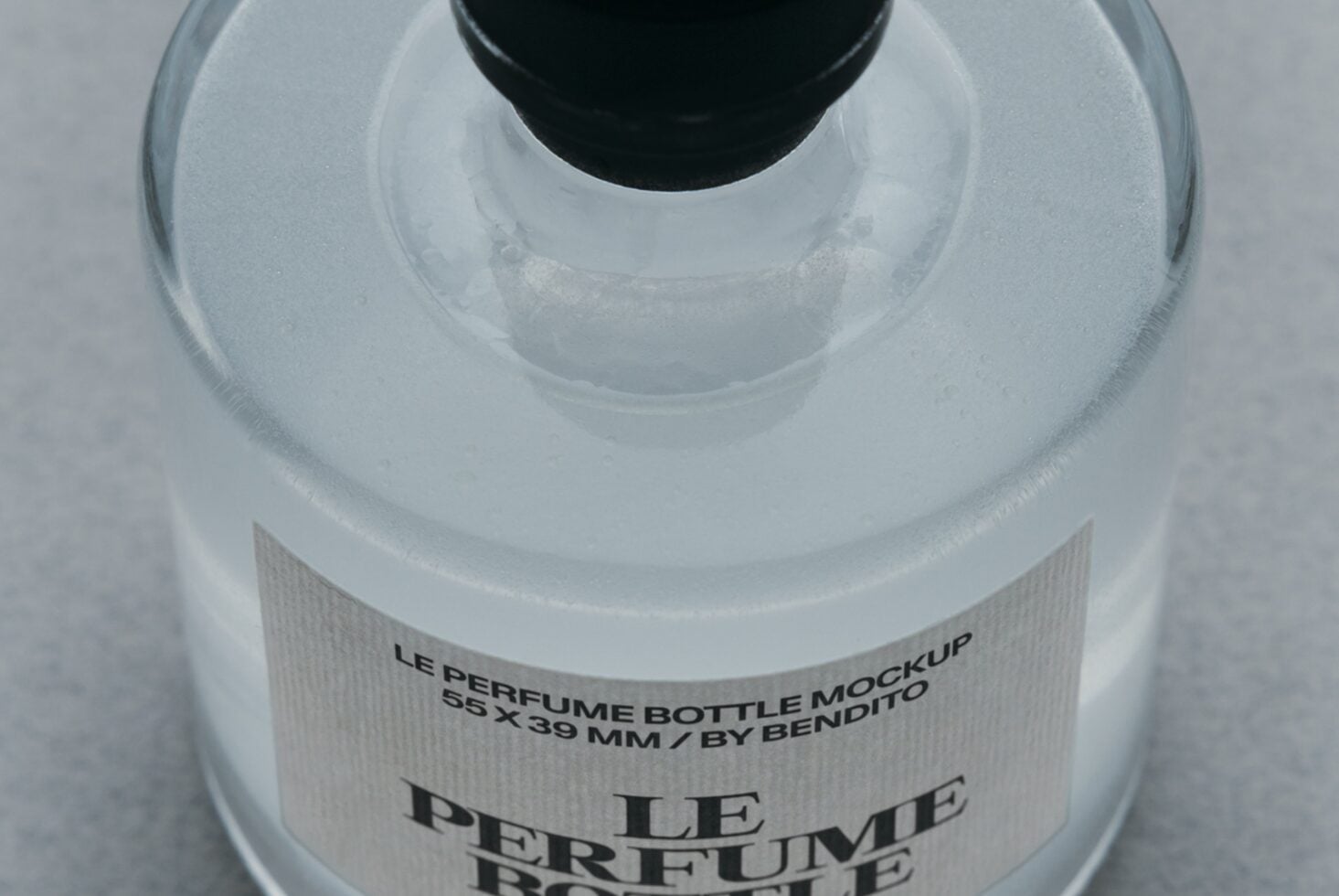Overhead shot of frosted glass perfume bottle with black cap, white textured label showing product details