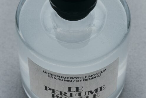 Overhead shot of frosted glass perfume bottle with black cap, white textured label showing product details