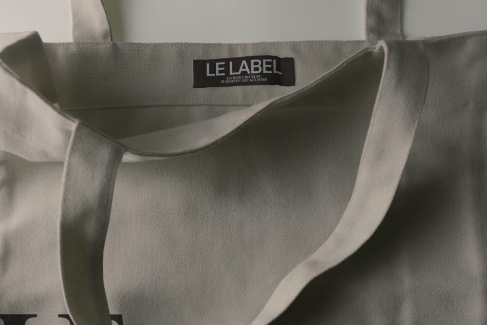 Beige canvas tote bag with black woven label showing "LE LABEL" branding
