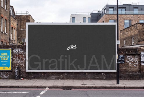 Large billboard mockup on brick urban street with white frame, dark display surface showing GrafikJAM logo