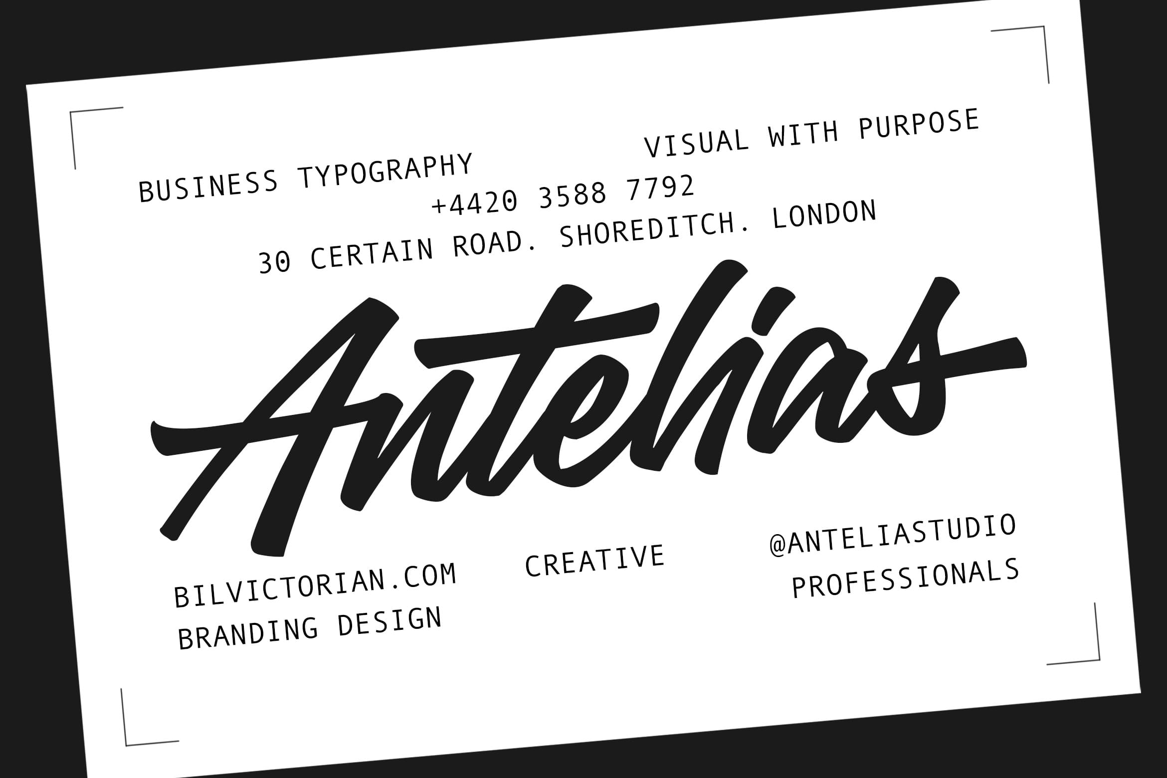 Tilted business card mockup with bold italic script logo, contact details, London address, minimal corner brackets