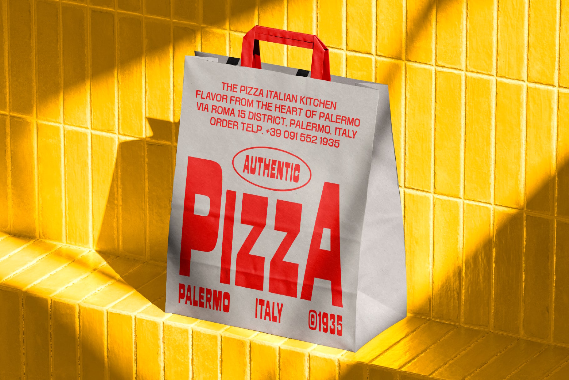 White paper bag with red handles showing bold "AUTHENTIC PIZZA" branding, Palermo Italy details against bright yellow tile wall