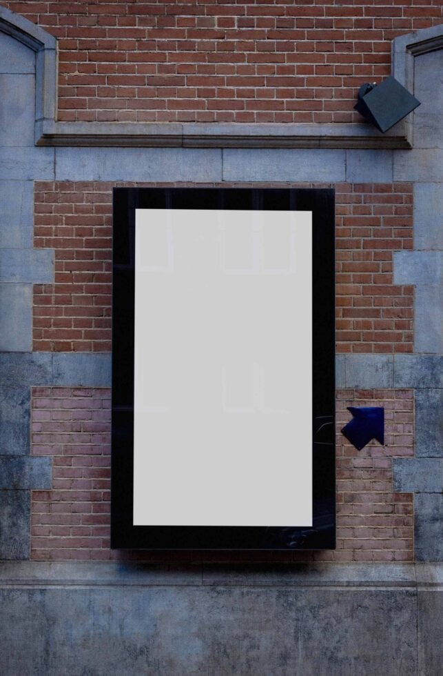 Black frame poster mockup on brick wall with concrete blocks, blank space ready to go