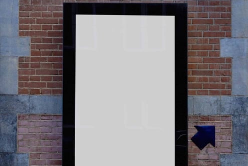 Blank poster mockup on brick wall with black frame, blue arrow pointing right