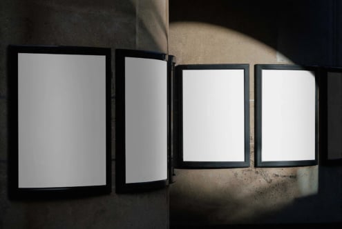 Black framed posters on concrete wall with dramatic sunlight casting shadows
