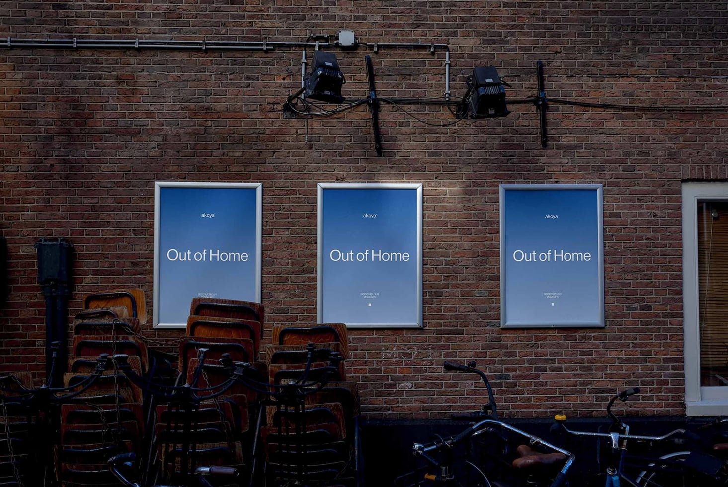 Street-facing brick wall with three illuminated poster mockups displaying "Out of Home" campaign