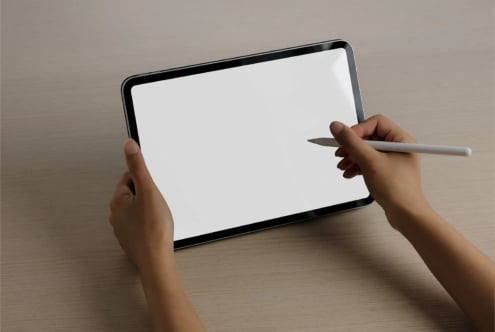 Hands holding tablet with stylus pen, blank screen ready for design work