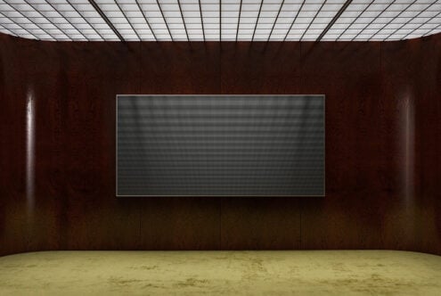 Modern gallery space with dark wood walls, grid ceiling, concrete floor, blank screen mockup