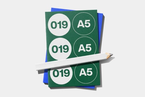 Stacked A5 brochures with circular badge designs, pencil laying across mockup