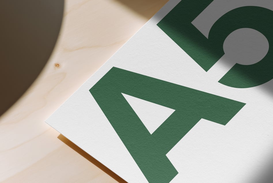 White paper with green geometric shapes on natural wood surface with soft shadows