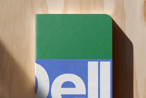 Green notebook with blue geometric design on wooden surface casting shadow