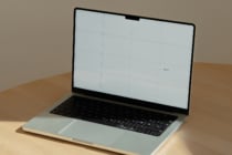 Laptop mockup on wood desk with gridded screen showing editable layout space