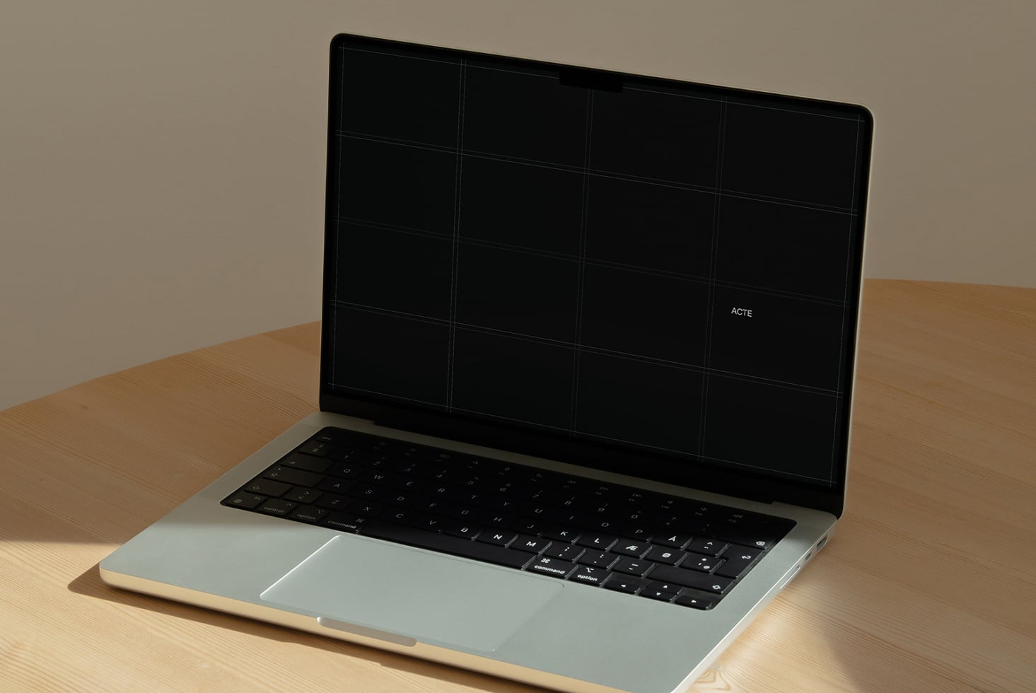 Laptop mockup on wooden desk with grid layout on screen, minimal branding visible