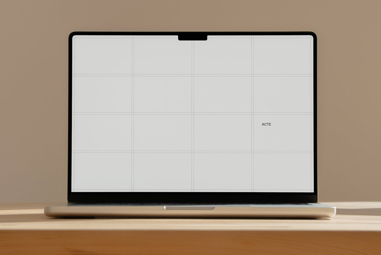 Laptop mockup with blank grid layout on screen, sitting on wooden desk
