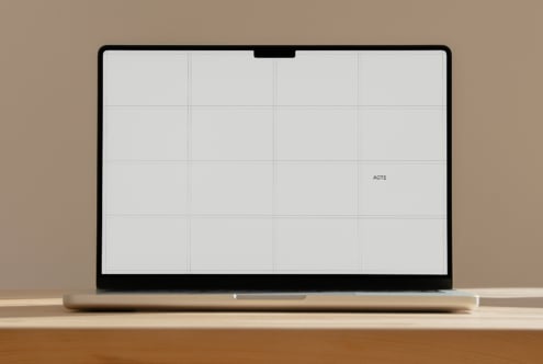 Laptop mockup with blank grid layout on screen, sitting on wooden desk