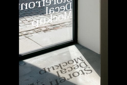 Storefront window with white neon signage casting shadows on concrete floor below