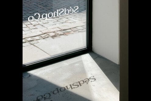 Window display mockup with storefront text on glass, concrete floor, natural sunlight casting shadows