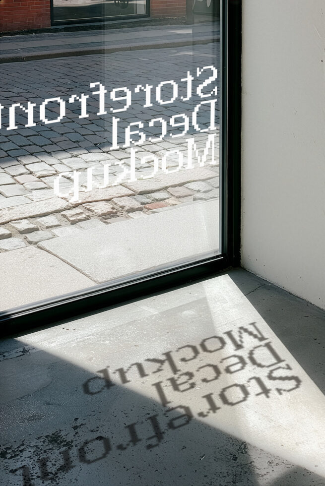 Window storefront with white pixelated text overlay casting shadows on pavement below