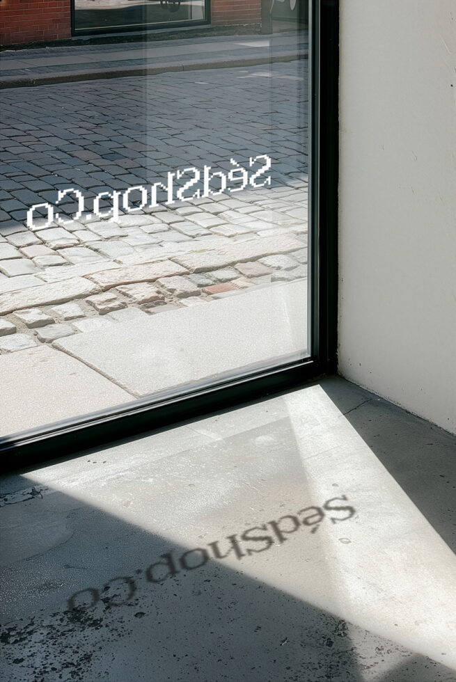 Window reflection mockup showing storefront glass with text overlay in bright sunlight casting shadows