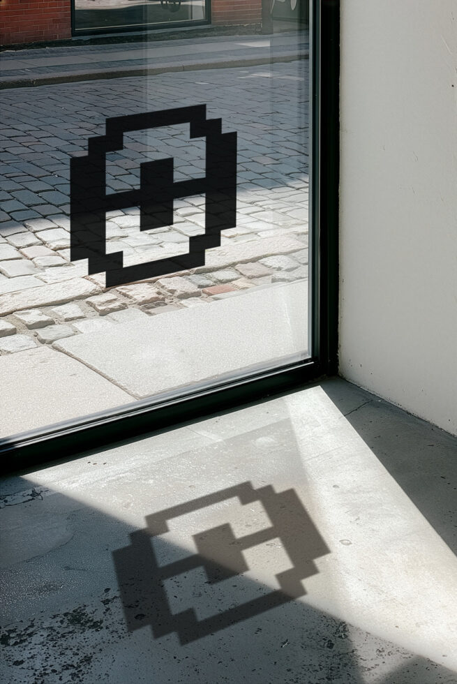 Black geometric shadow cast on pavement through storefront window with brick building