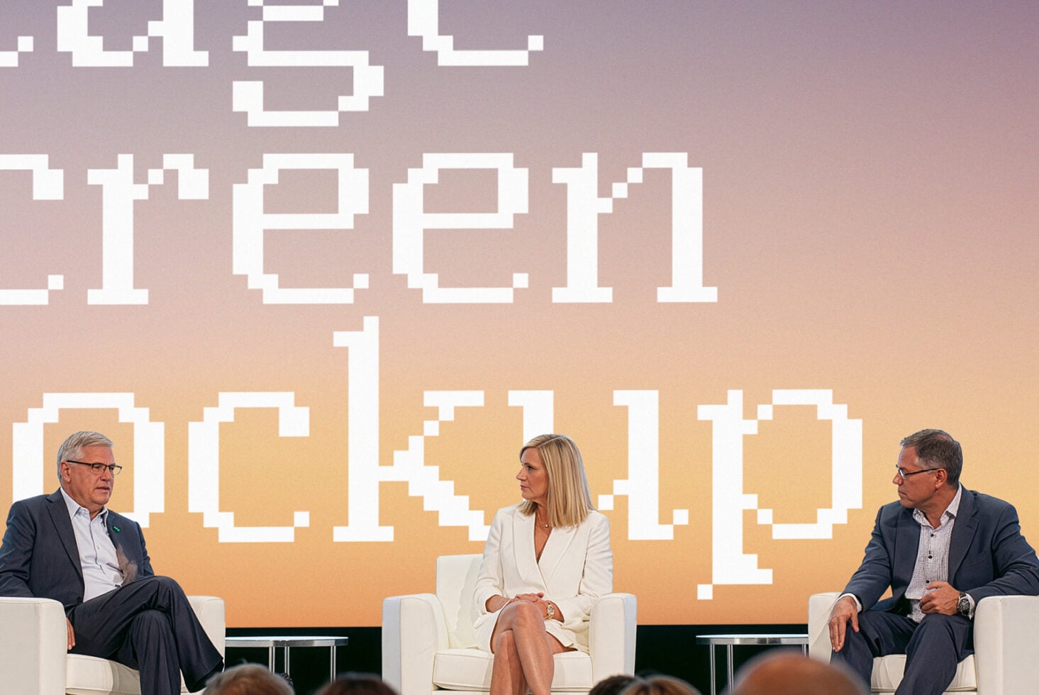 Three people seated for panel discussion with pixelated gradient backdrop behind them