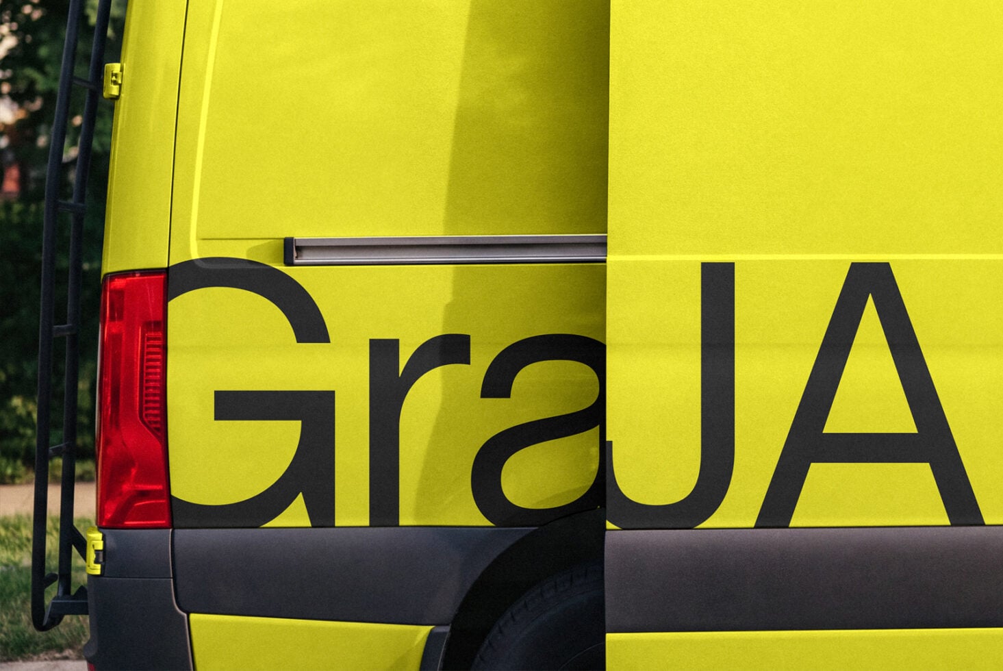 Neon yellow van with bold black text on side, red taillight visible, parked outdoors