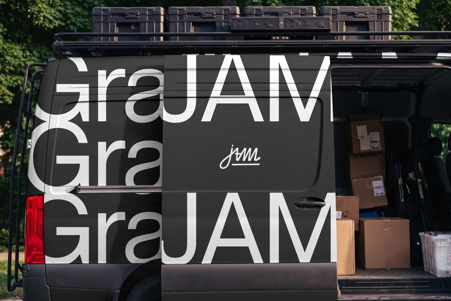 Black van with oversized GraJAM branding, loaded boxes visible inside, green foliage behind