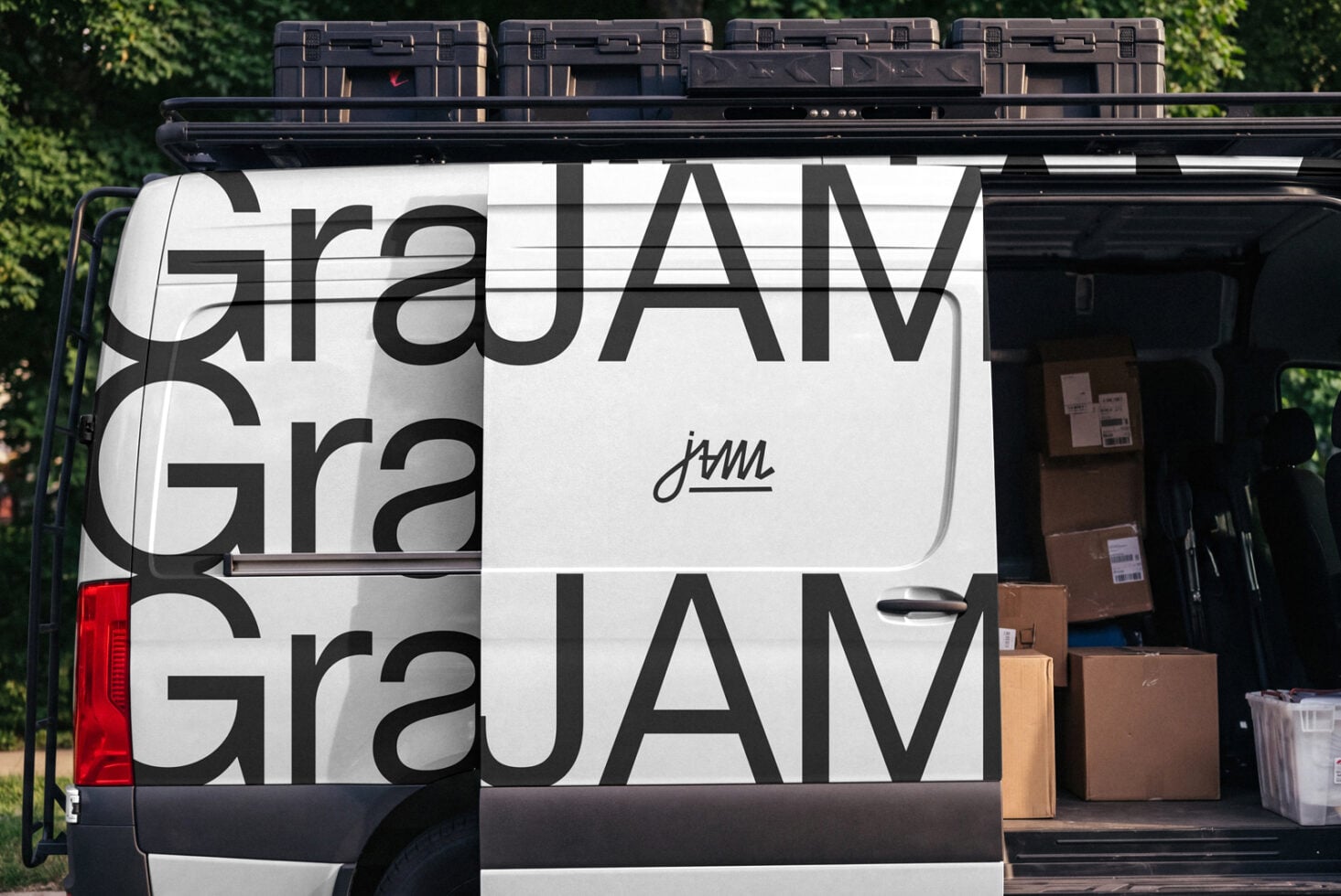 Van wrap mockup with bold geometric type, cargo boxes stacked inside, black roof rack with cases