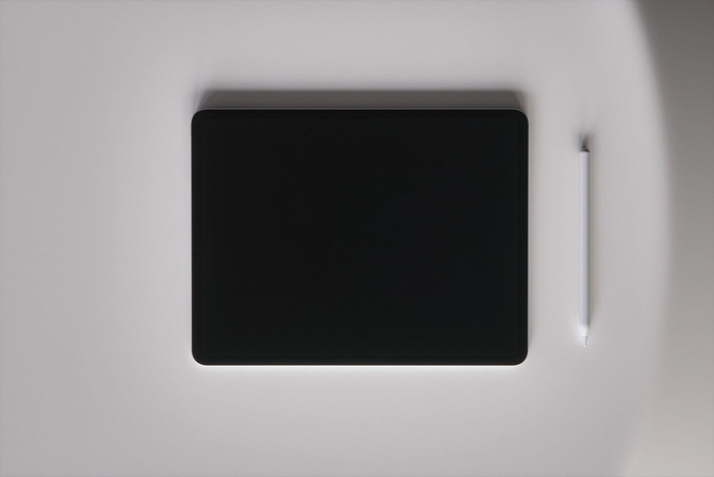 Tablet with stylus on neutral gray surface, overhead shot